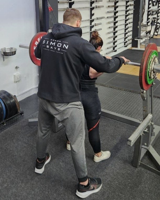 Simon coaching a client through a squat at Performance Purist